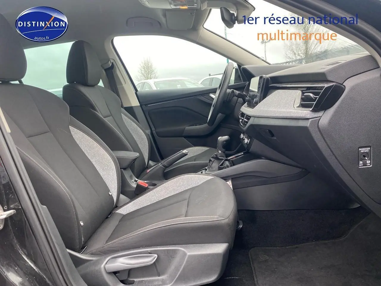 Vue intérieure côté gauche du Skoda Kamiq noir 2025, montrant sièges avant bi-matière et tableau de bord moderne.