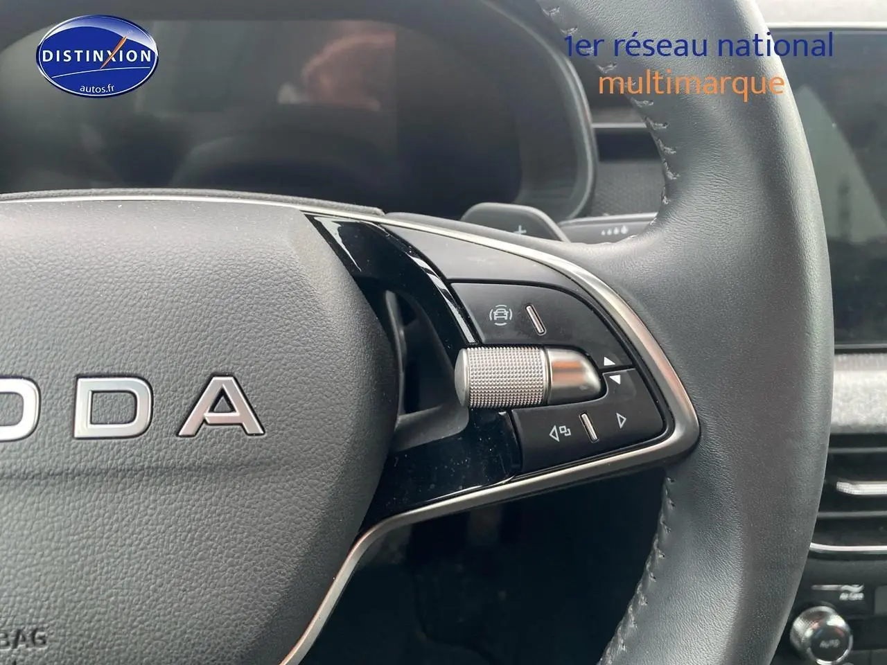 Gros plan sur le volant cuir noir du Skoda Kamiq 2025, avec commandes multifonctions et molette argentée à droite.