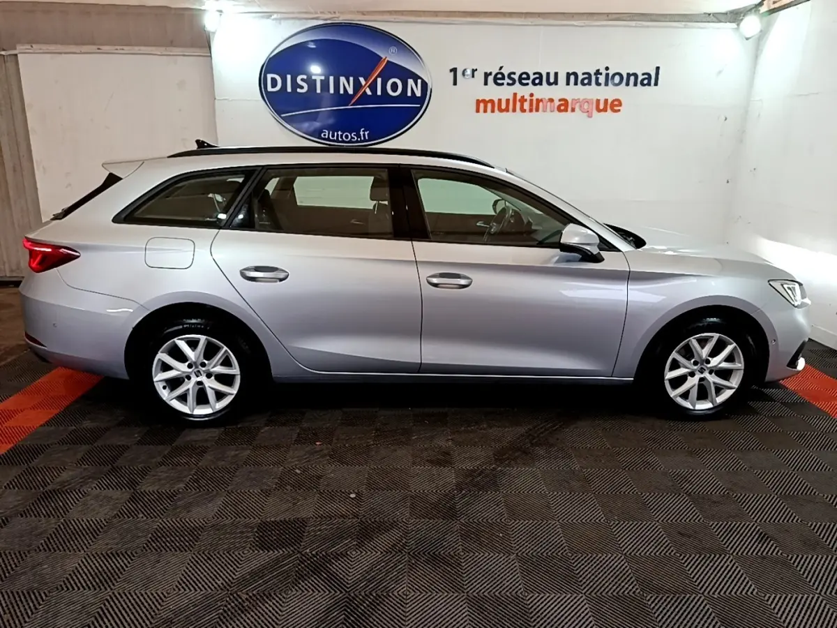 Vue latérale droite d'une SEAT Leon gris foncé break 2022 en intérieur avec jantes alliage et toit ouvrant.