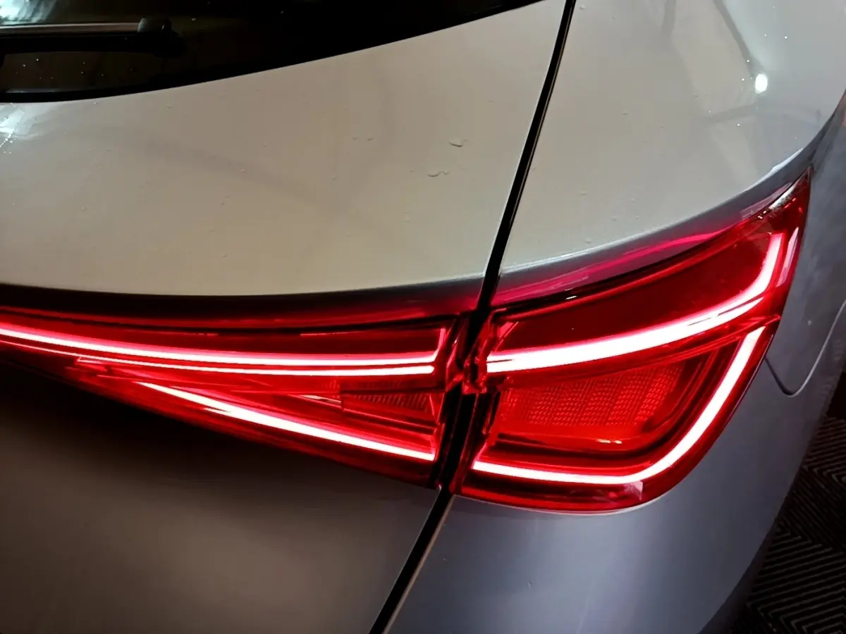 Gros plan sur le feu arrière droit rouge allumé du SEAT LEON gris foncé, soulignant la ligne de coffre.