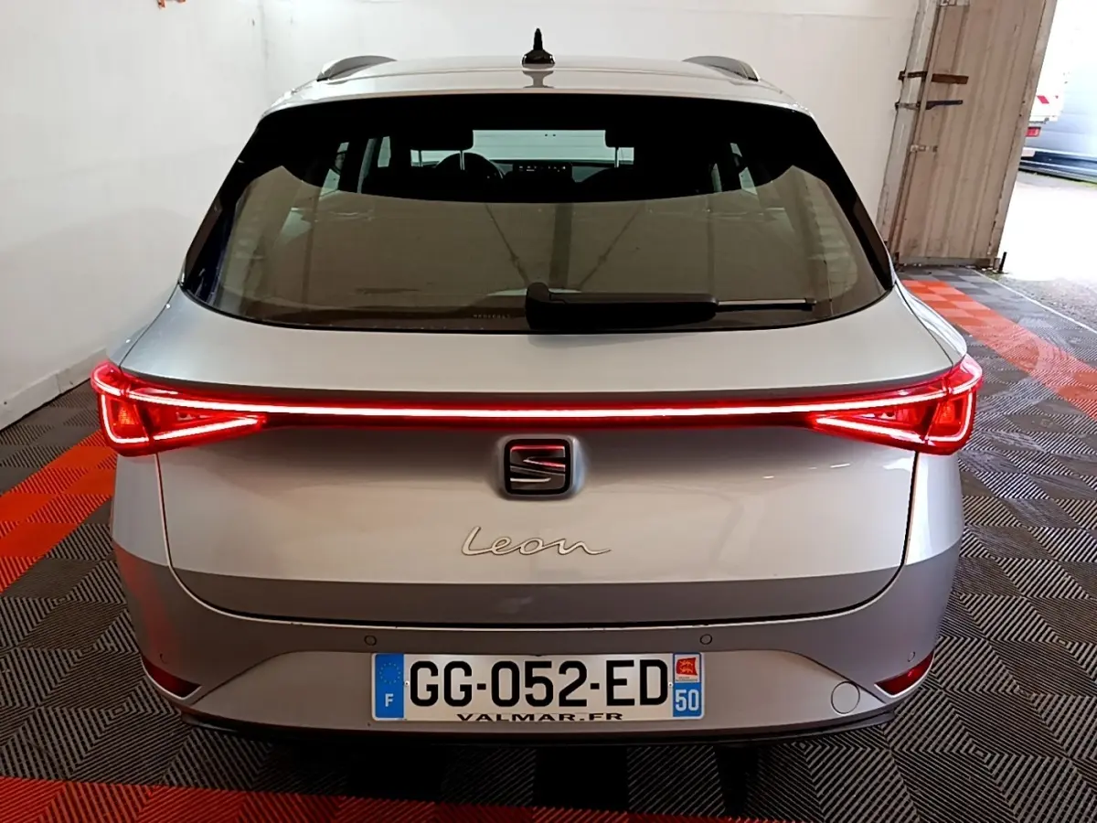 Vue arrière d'une SEAT Leon gris clair avec feux arrière LED allumés dans un garage.