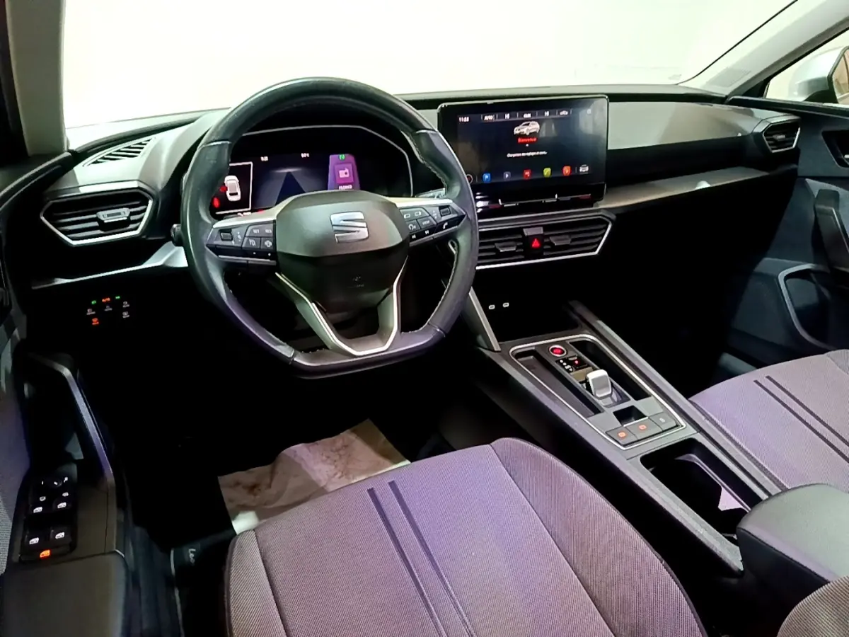 Vue intérieure avant droite du tableau de bord et volant cuir alu de la SEAT Leon gris foncé avec écran tactile central.