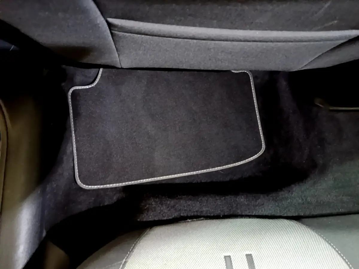 Vue rapprochée du tapis de sol noir et de la moquette sous le siège arrière d'une SEAT Leon gris foncé.