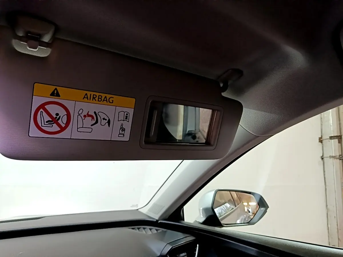 Vue intérieure côté passager de la SEAT Leon gris foncé 2022, avec pare-soleil rabattu et miroir de courtoisie visible.