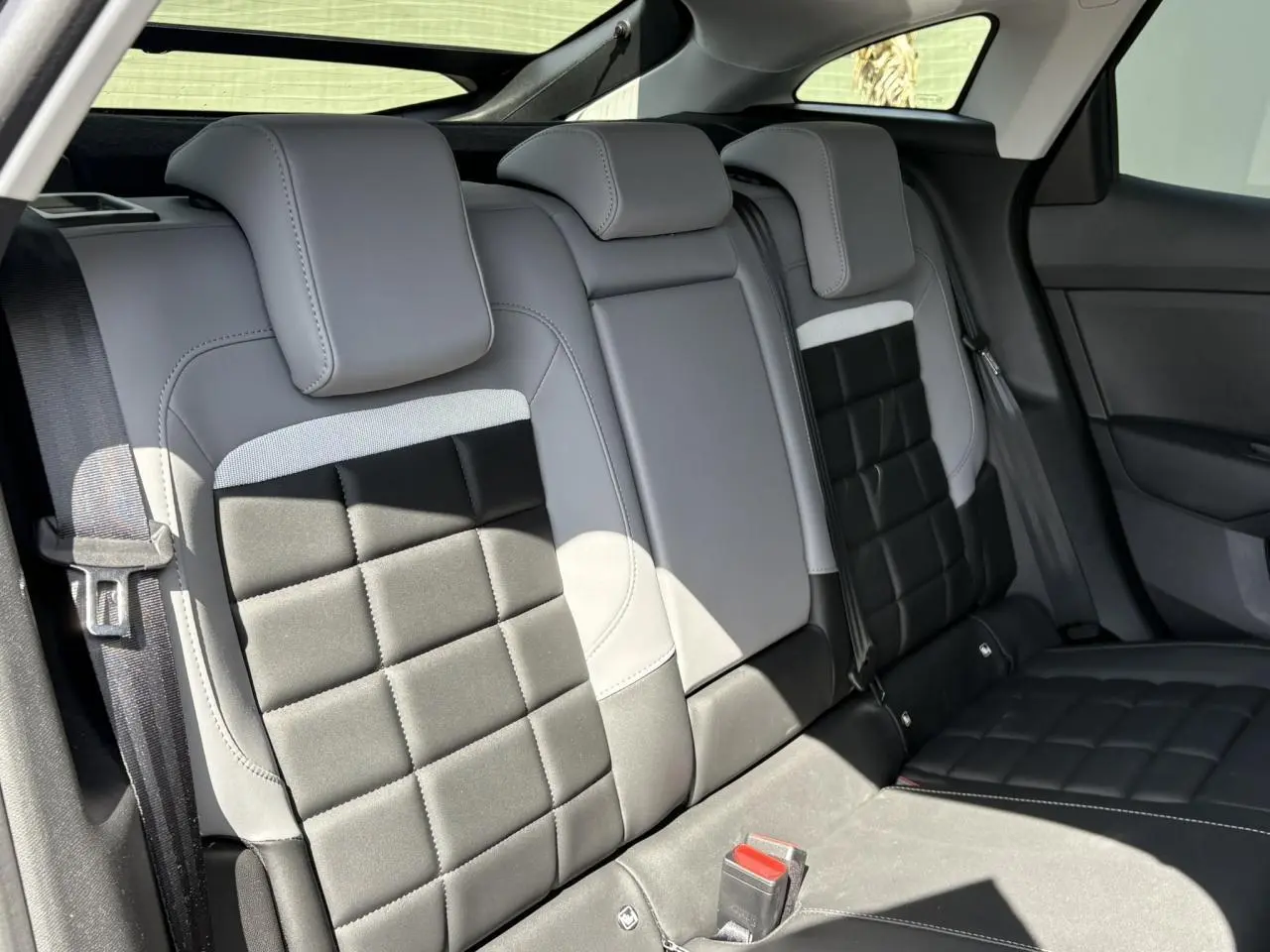 Vue intérieure des sièges arrière gris clair et noir de la Citroën C4 Hybrid 2025, avec ceintures de sécurité visibles.