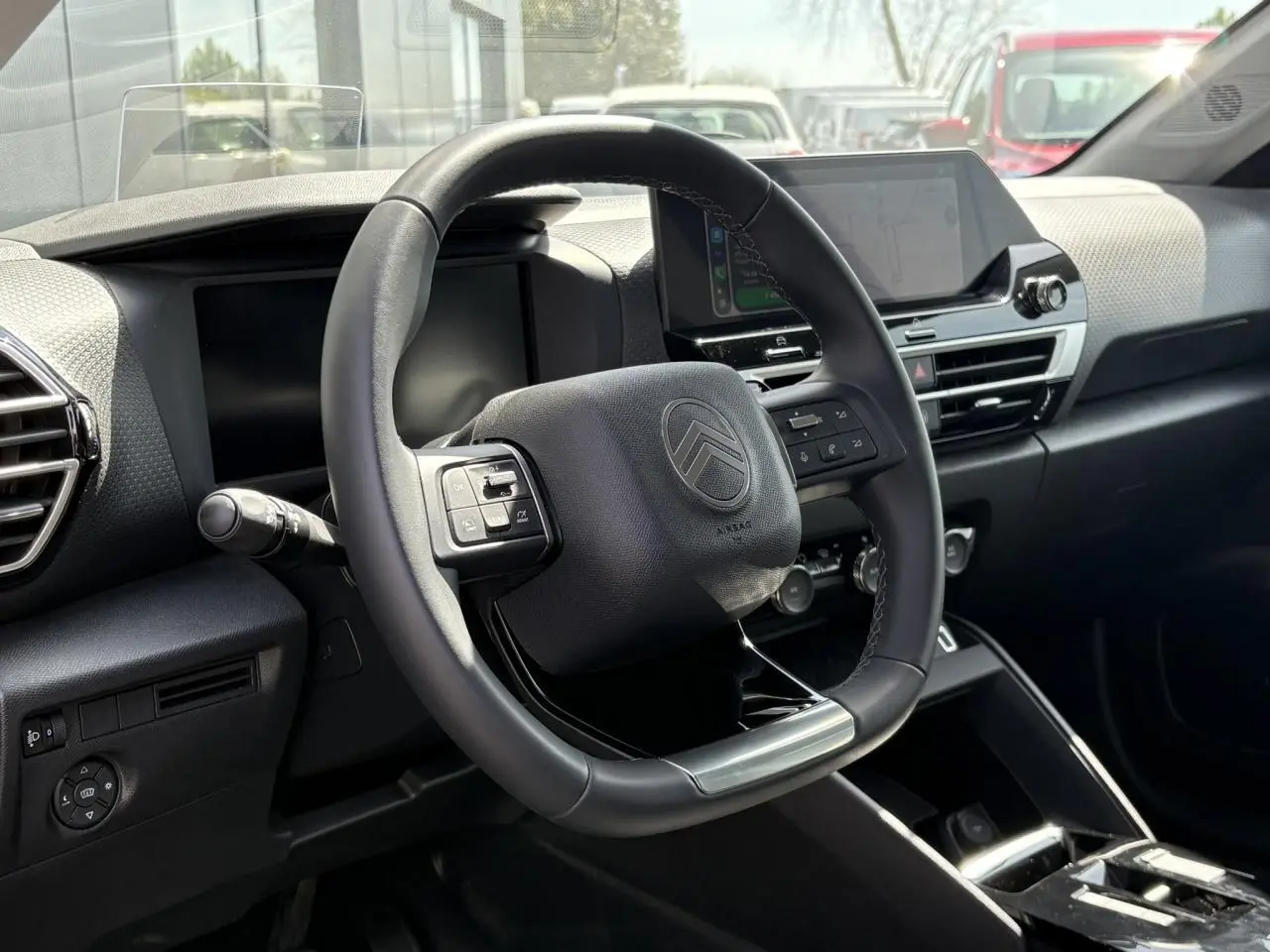 Vue intérieure centrée sur le volant cuir du Citroën C4 Hybrid 2025 avec écran tactile et tableau de bord noir.