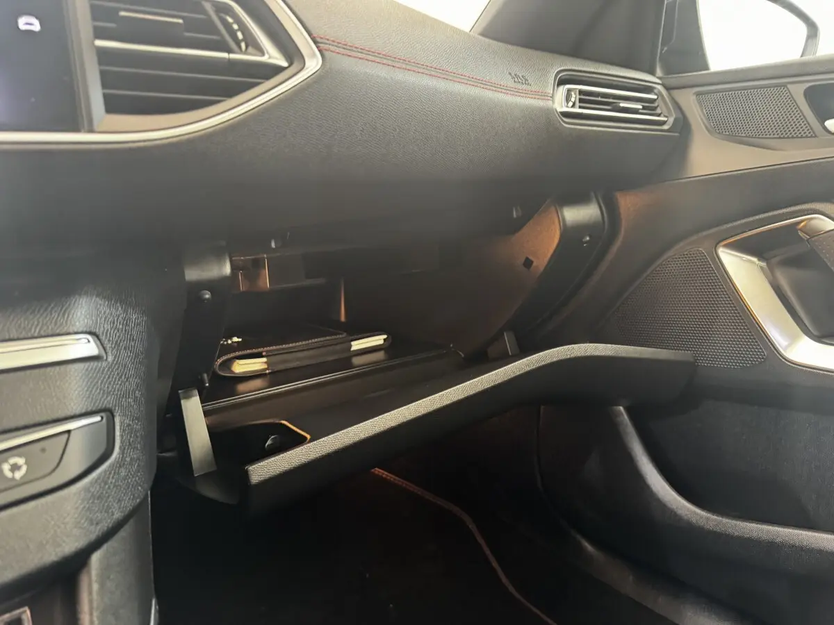 Vue intérieure côté passager de la Peugeot 308 GT Line 2018, boîte à gants ouverte avec éclairage ambiant rouge.