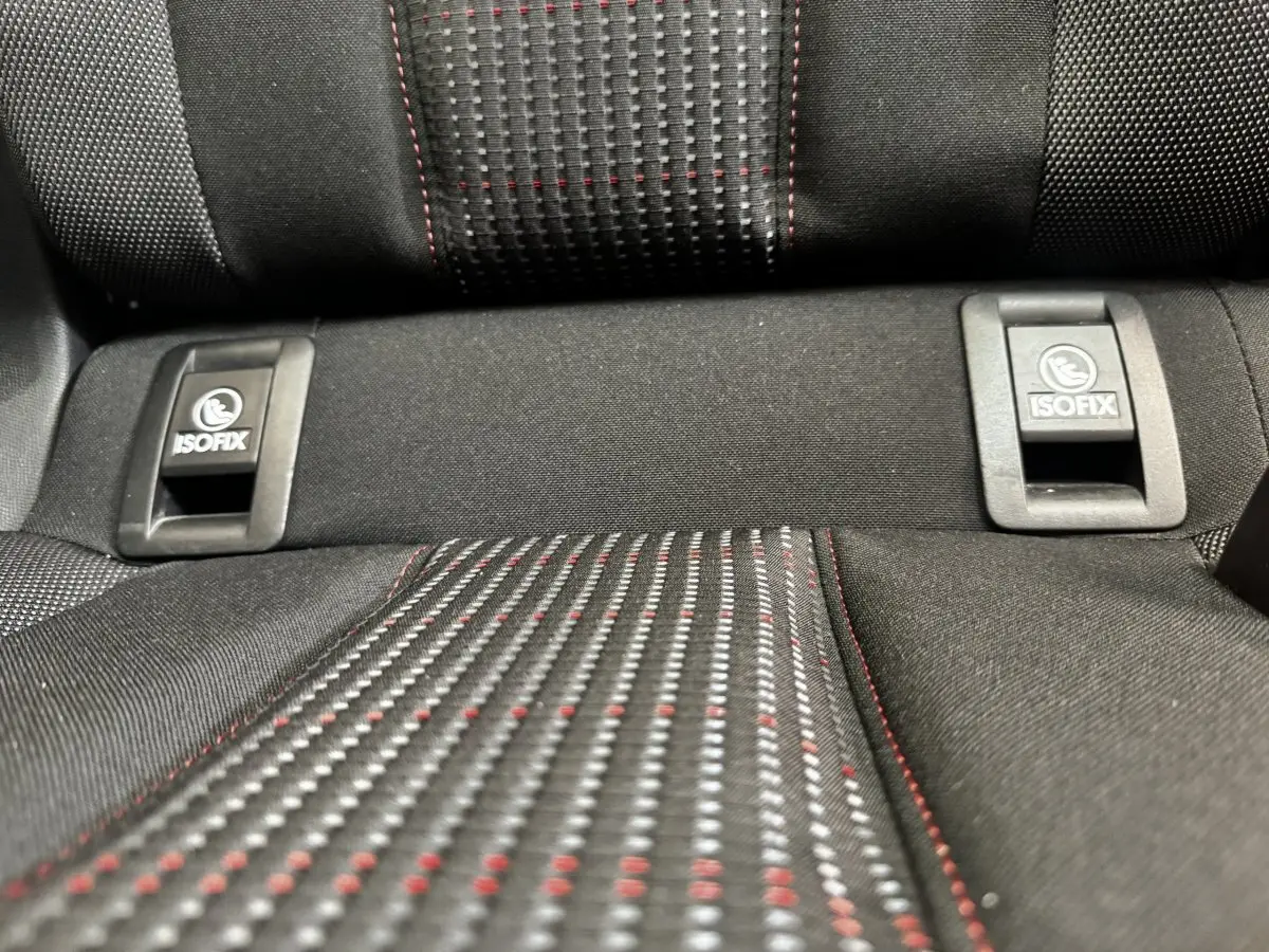 Gros plan sur la banquette arrière noire de la Peugeot 308 avec fixation ISOFIX et surpiqûres rouges.