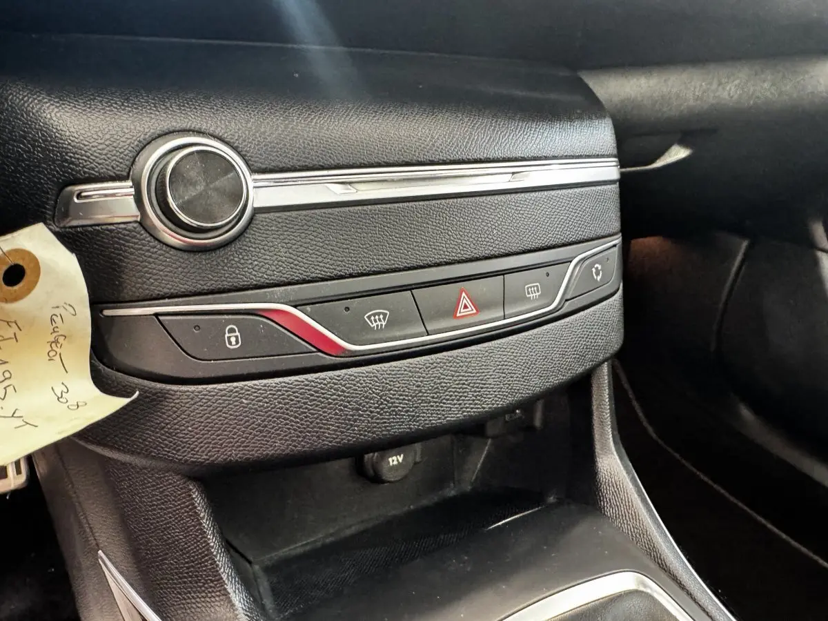 Détail de la console centrale noire de la Peugeot 308 2018 avec commandes de verrouillage et dégivrage, prise 12V visible.