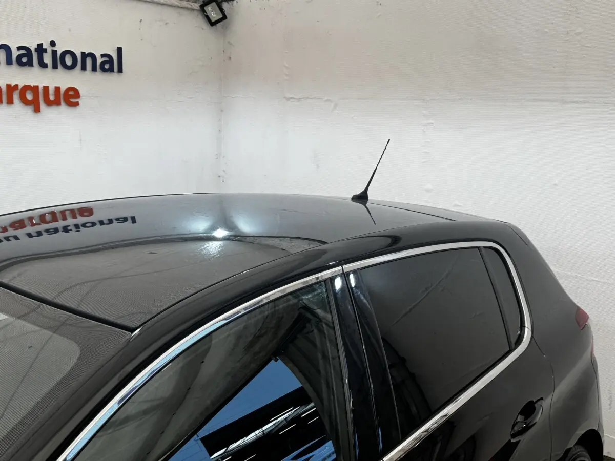 Vue 3/4 arrière droite d'une Peugeot 308 noire avec vitres teintées et antenne de toit visible.