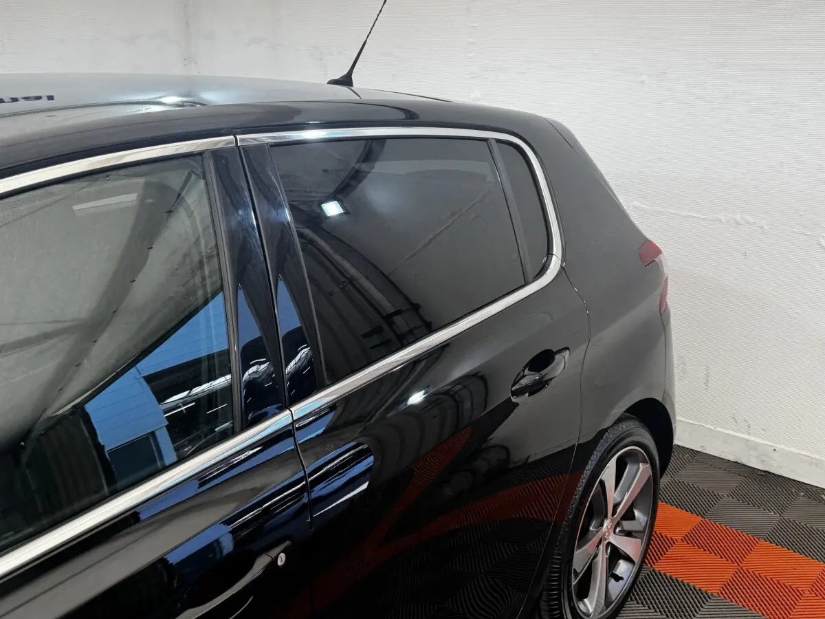 Vue côté droit arrière d’une Peugeot 308 noire 2018 avec jantes alliage et vitres teintées.