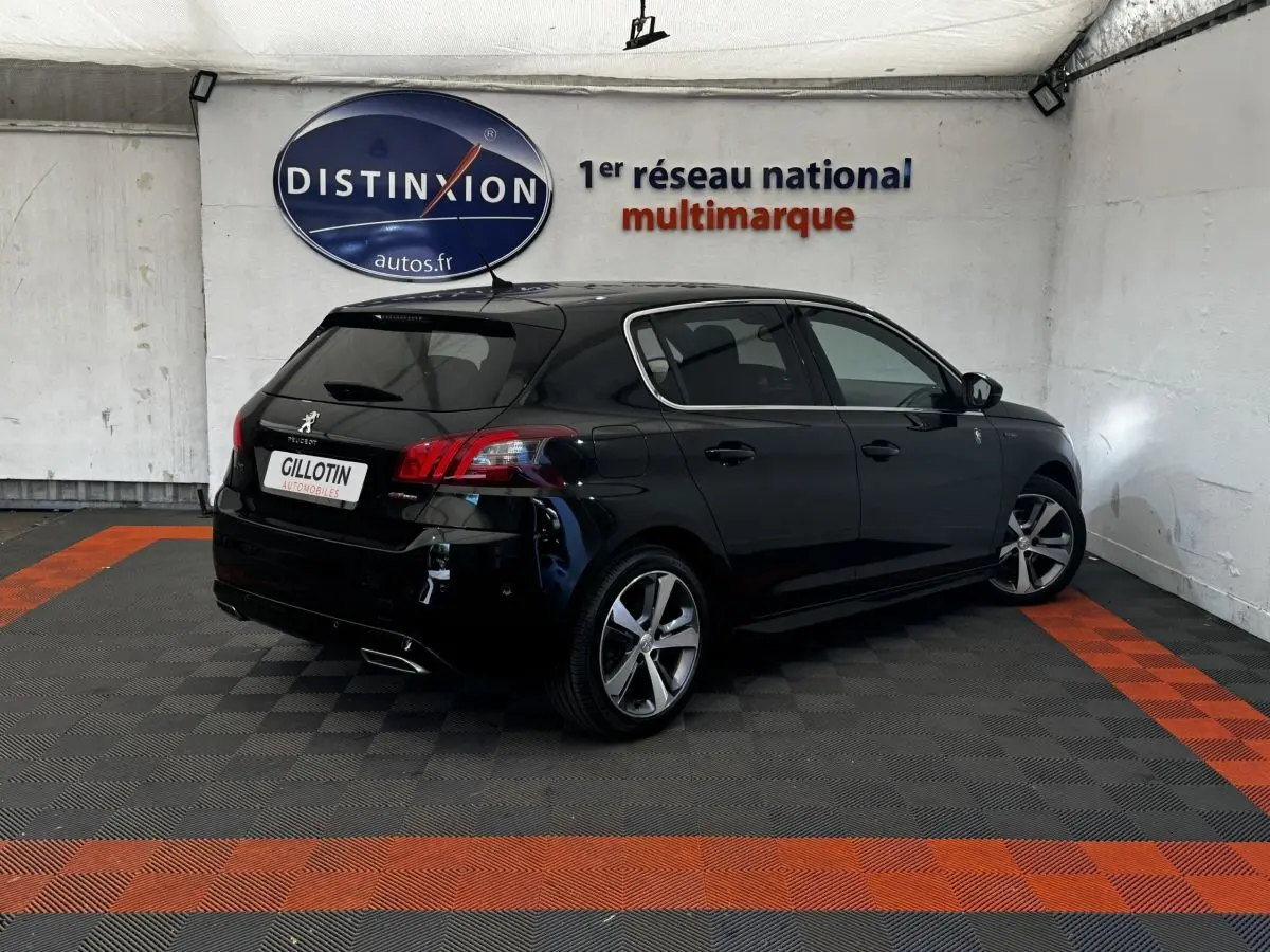 Peugeot 308 noire vue 3/4 arrière droit dans un garage avec jantes alliage et feux LED distinctifs.