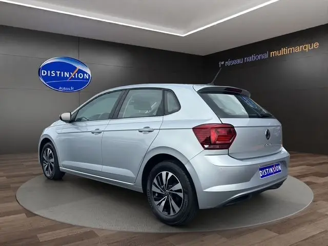 Vue 3/4 arrière droite d'une Volkswagen Polo VI Lounge Business gris clair en intérieur showroom avec jantes alliage 15 pouces.