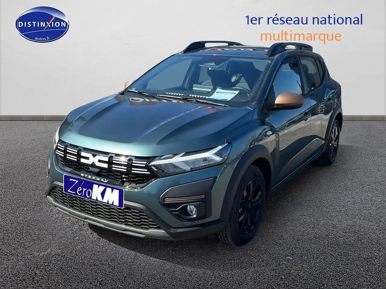 Vue 3/4 avant droite d'une Dacia Sandero Stepway 2025 vert cèdre avec jantes noires et barres de toit.