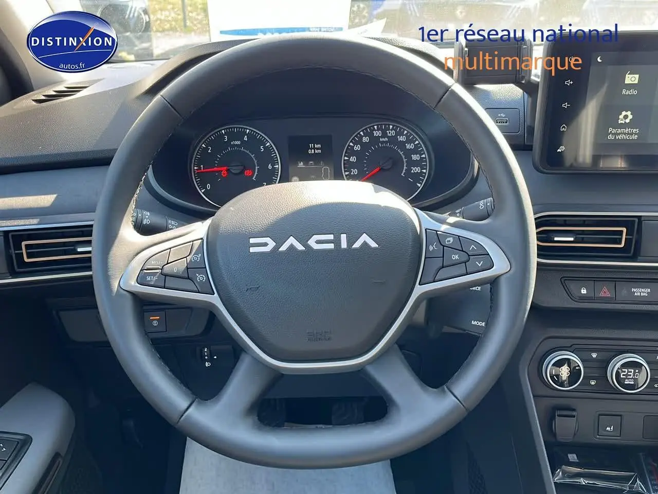 Vue rapprochée du volant multifonction DACIA Sandero 2025 avec tableau de bord et écran tactile visibles.