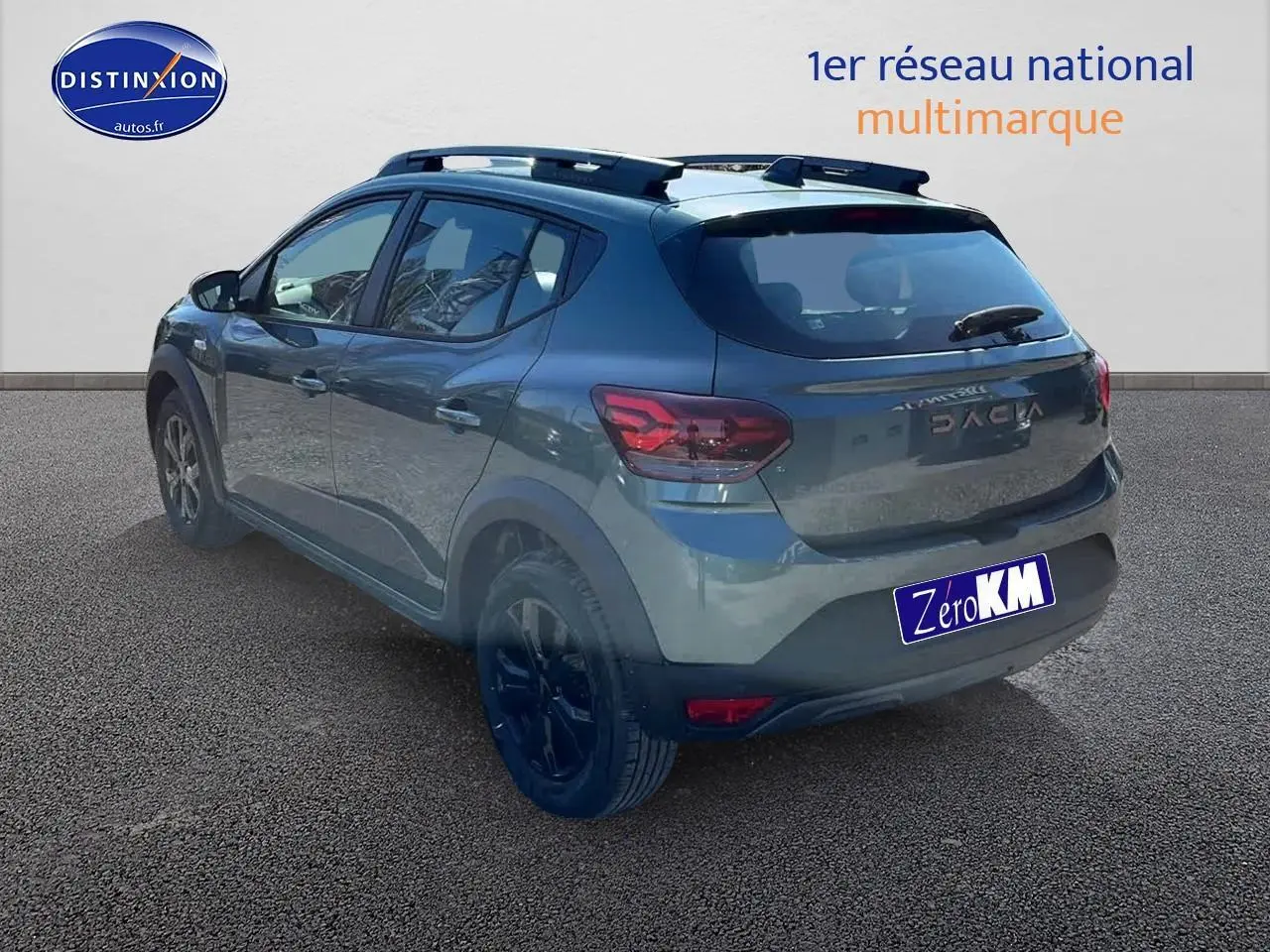 Vue 3/4 arrière droite d'une Dacia Sandero 2025 vert cèdre avec jantes alu et barres de toit visibles.