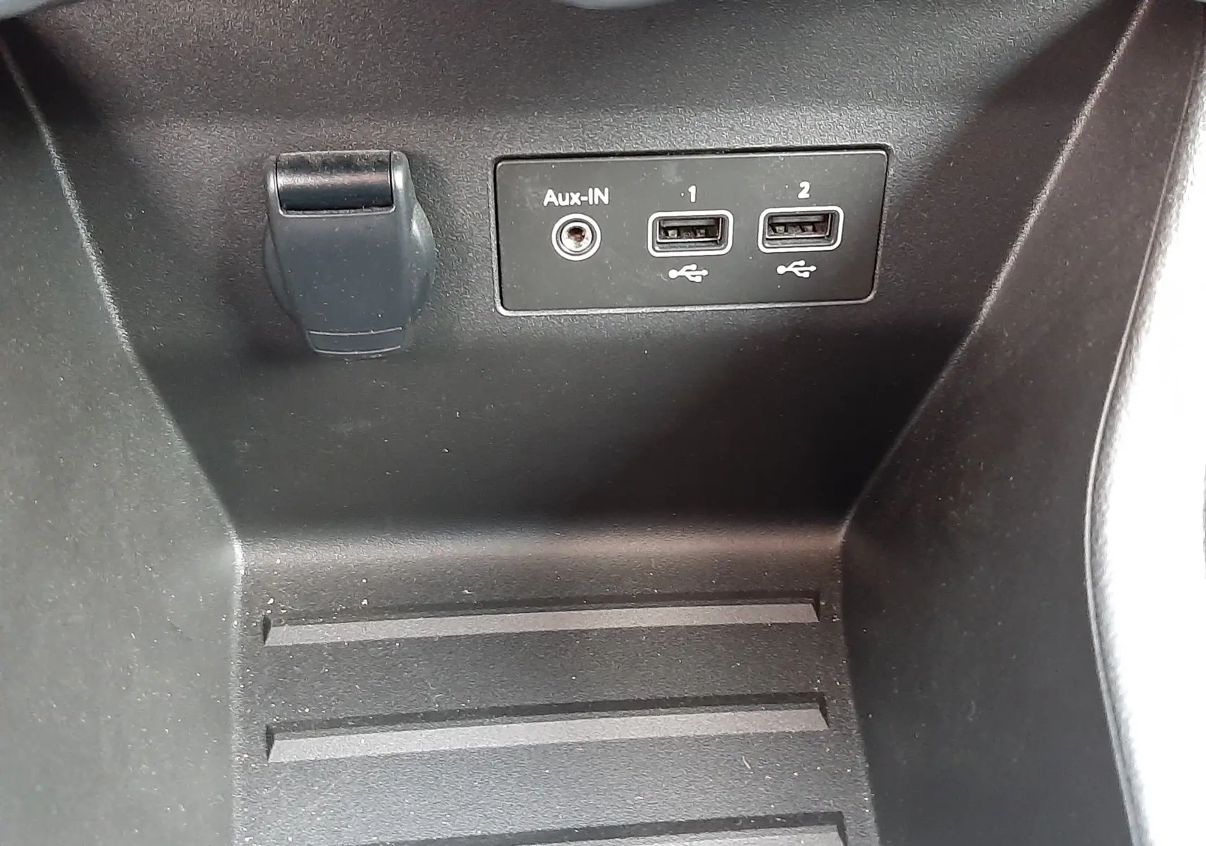 Gros plan sur la console centrale noire de la Renault Clio V avec prises USB et entrée Aux-In visibles.