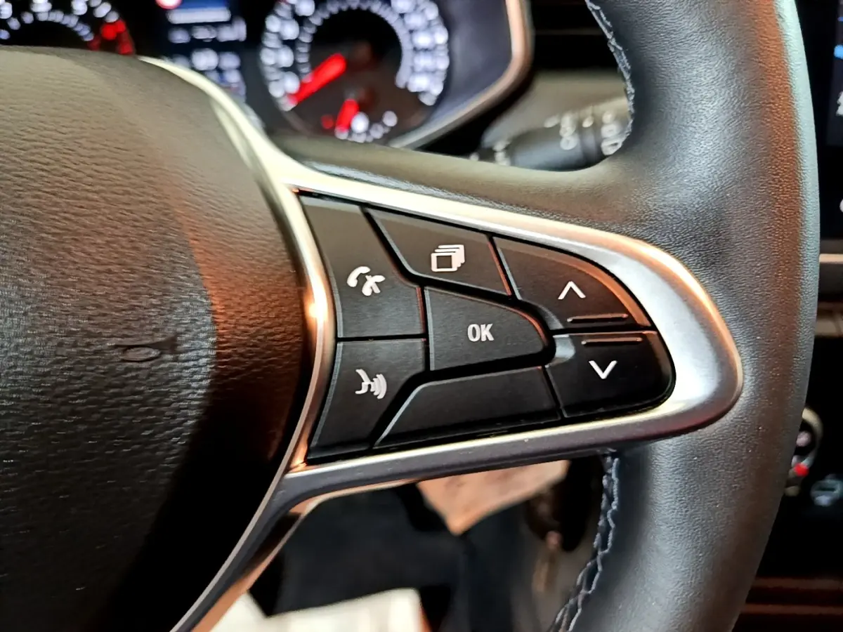 Gros plan sur les commandes multifonctions à droite du volant cuir noir de la Renault Clio Business blanche de 2021.