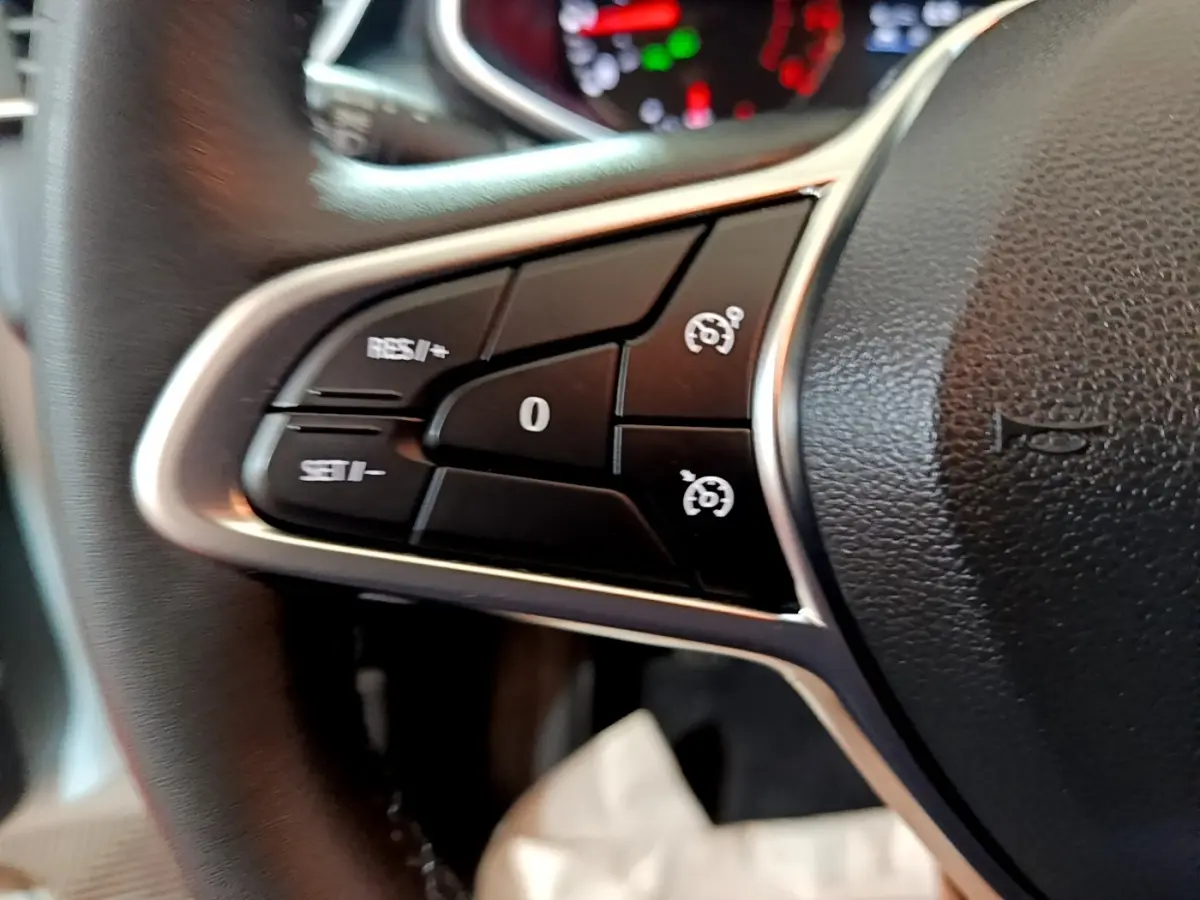 Gros plan sur les commandes au volant côté gauche d'une Renault Clio Business blanche, avec boutons de régulateur de vitesse.