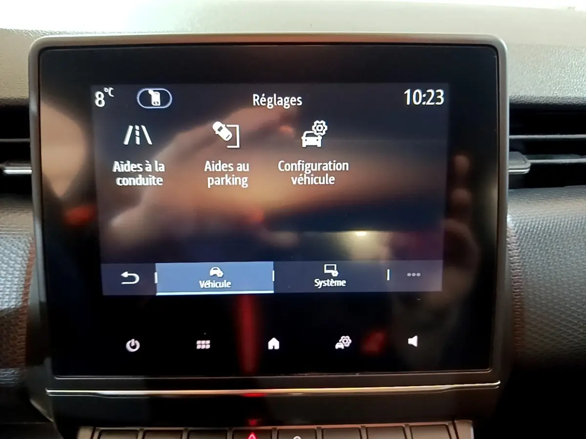 Écran tactile central du tableau de bord de la Renault Clio Business blanc, affichant les réglages d’aides à la conduite et parking.