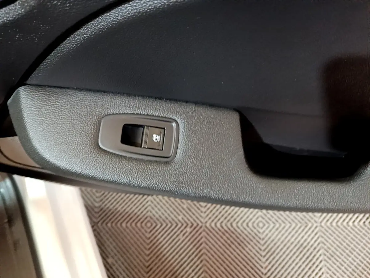 Gros plan sur le bouton de verrouillage des portes côté gauche de la porte intérieure d'une Renault Clio blanche.