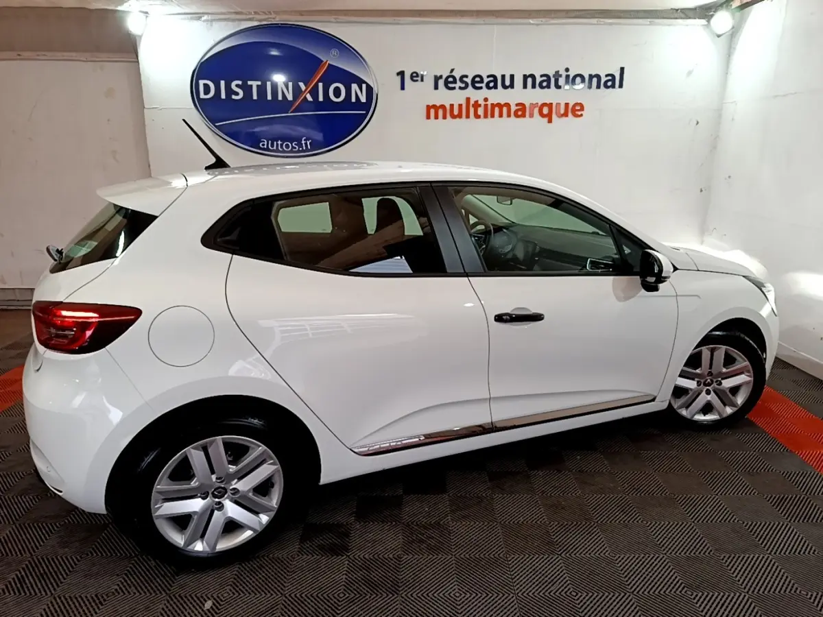 Renault Clio Business blanc vue de profil côté gauche, en intérieur avec jantes alliage et feux arrière allumés.