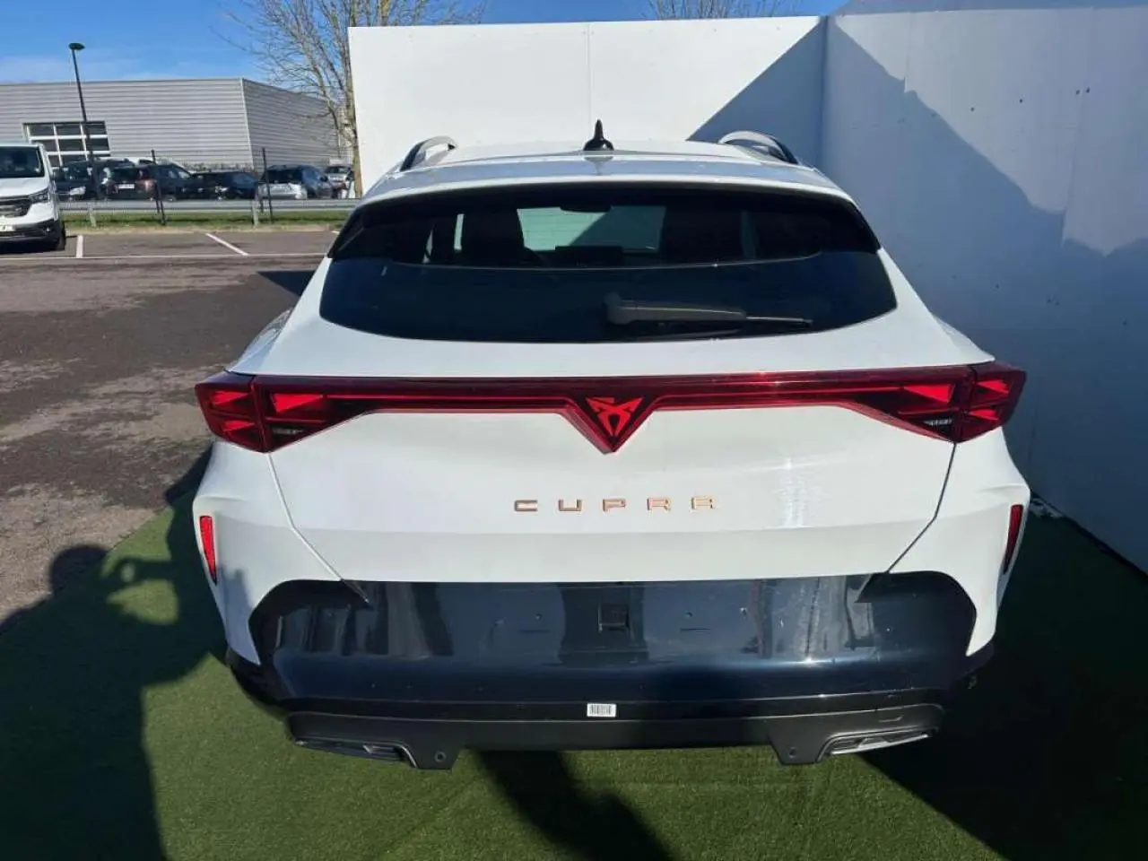 Vue arrière d'une CUPRA Formentor blanche 2025 avec signature lumineuse rouge et logo central distinctif.