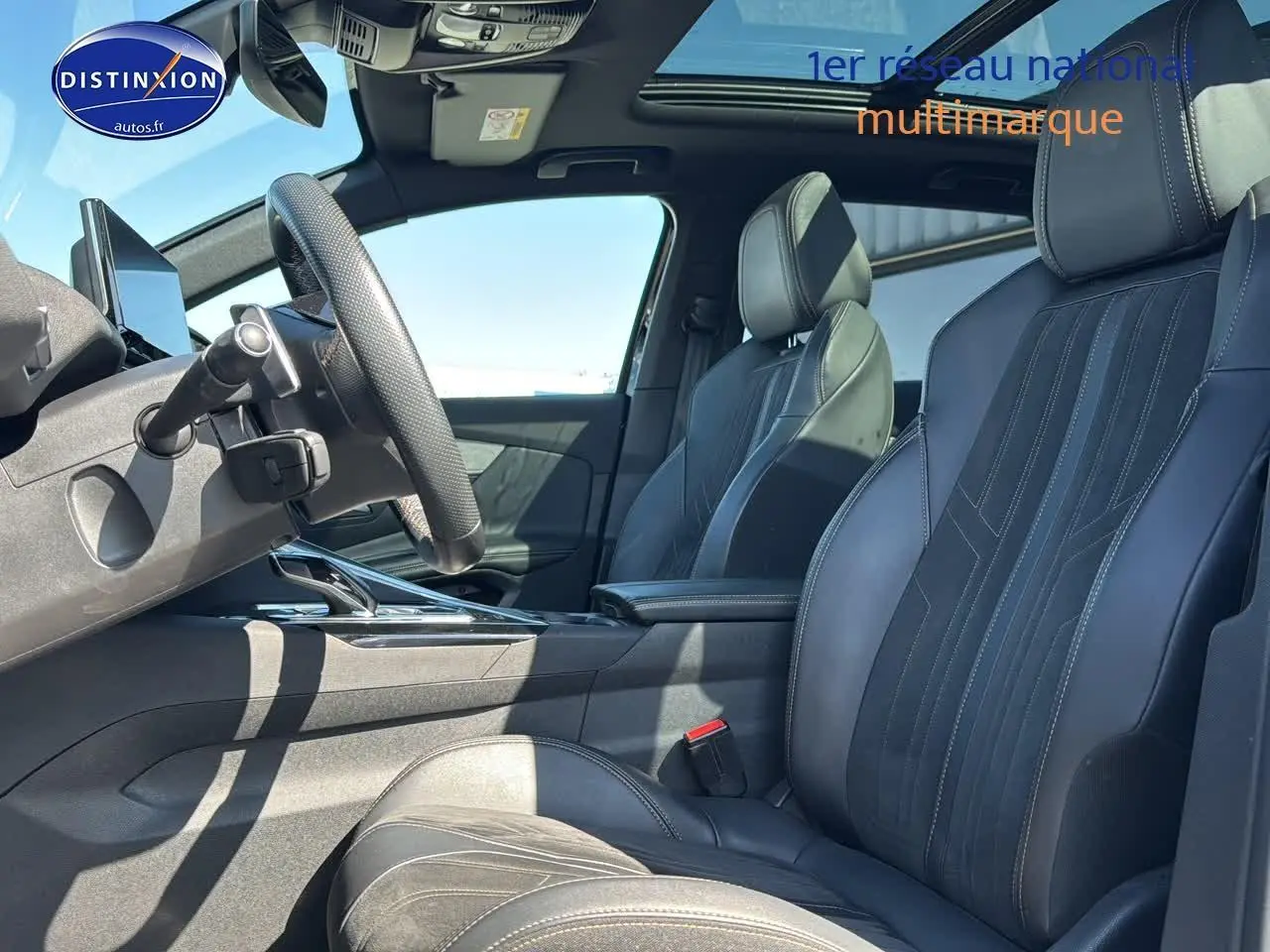 Intérieur du Peugeot 3008 2022, vue côté conducteur, sièges cuir noirs avec surpiqûres blanches et toit ouvrant panoramique.