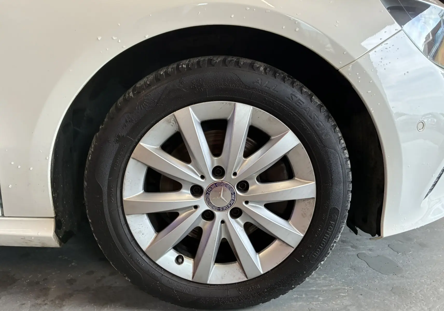 Gros plan sur la roue avant gauche d'une Mercedes Classe A 200D blanche avec jante alliage et logo central visible.