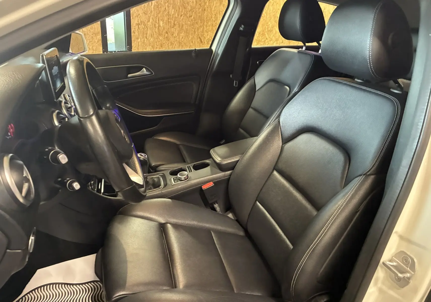 Vue intérieure côté conducteur de la Mercedes Classe A 200D 2016 avec sièges cuir noir et tableau de bord moderne.