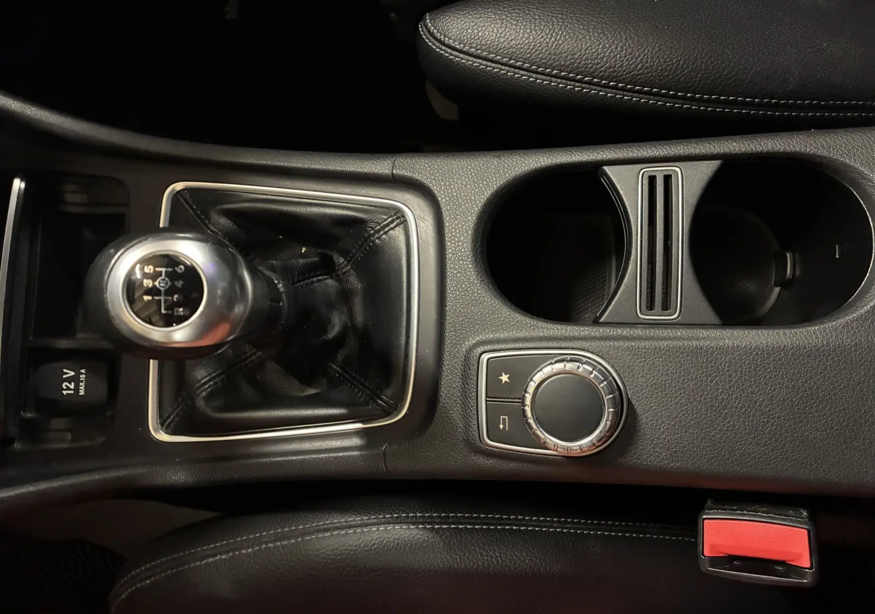 Vue rapprochée de la console centrale noire d'une Mercedes Classe A 200D 2016 avec levier de vitesse manuel et commandes circulaires.