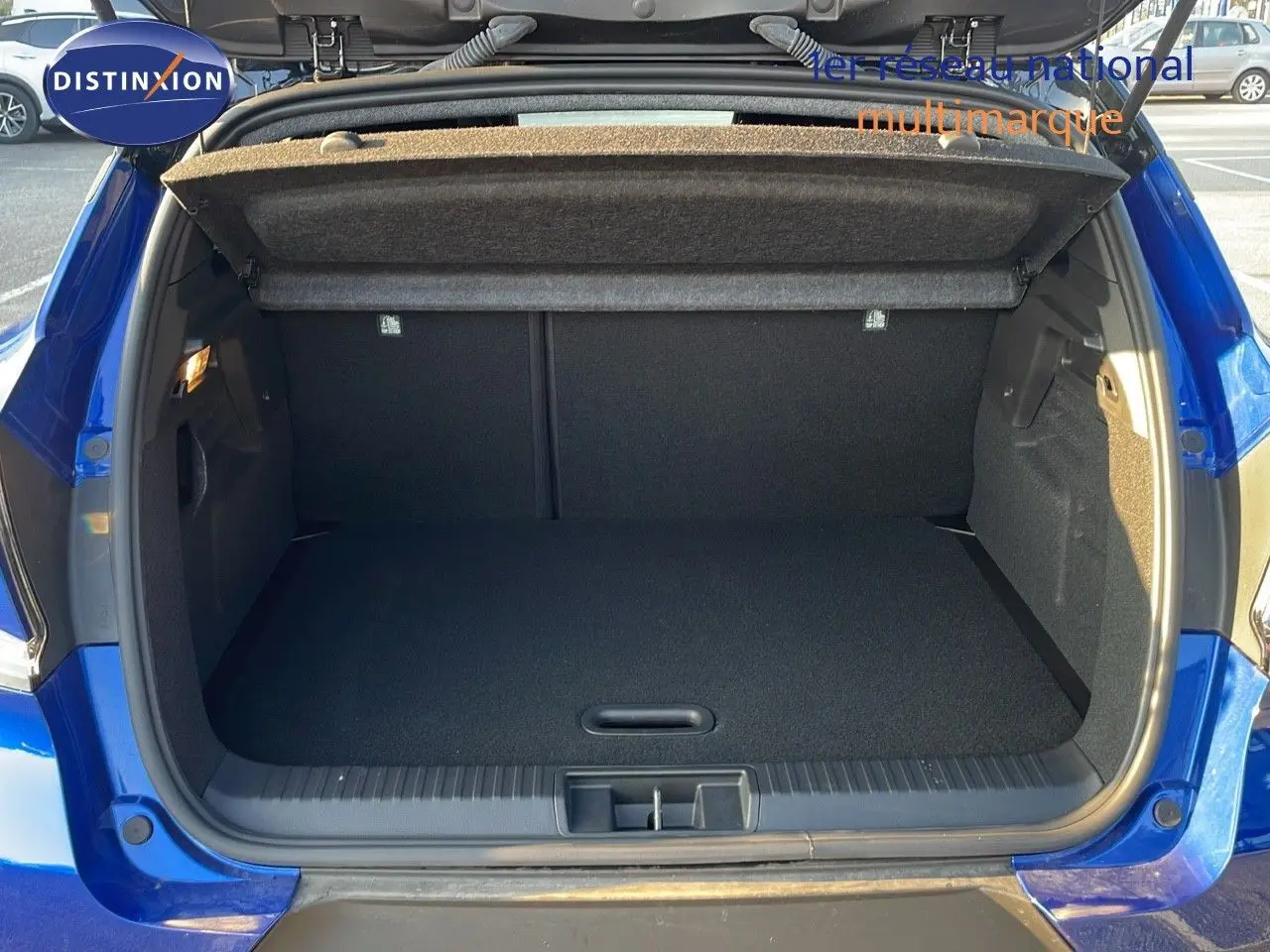 Coffre ouvert d'un Renault Captur E-Tech hybride 2025 bleu iron metal avec toit noir, vue arrière en extérieur.