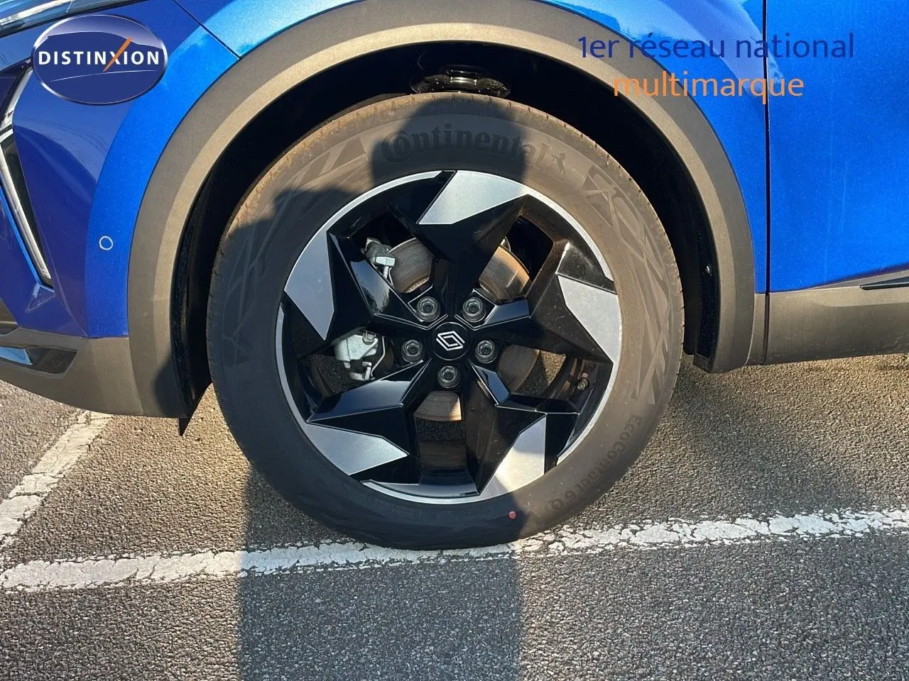 Gros plan sur la roue avant gauche du Renault Captur bleu Iron Metal avec jante noire et grise design moderne.