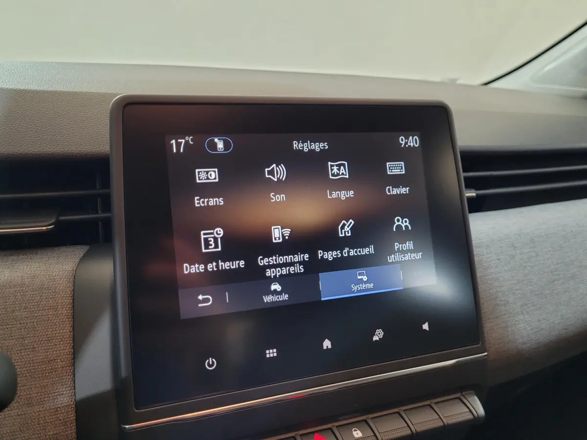 Écran tactile central de la Renault Clio bleu, vue rapprochée du tableau de bord avec menu Réglages affiché.