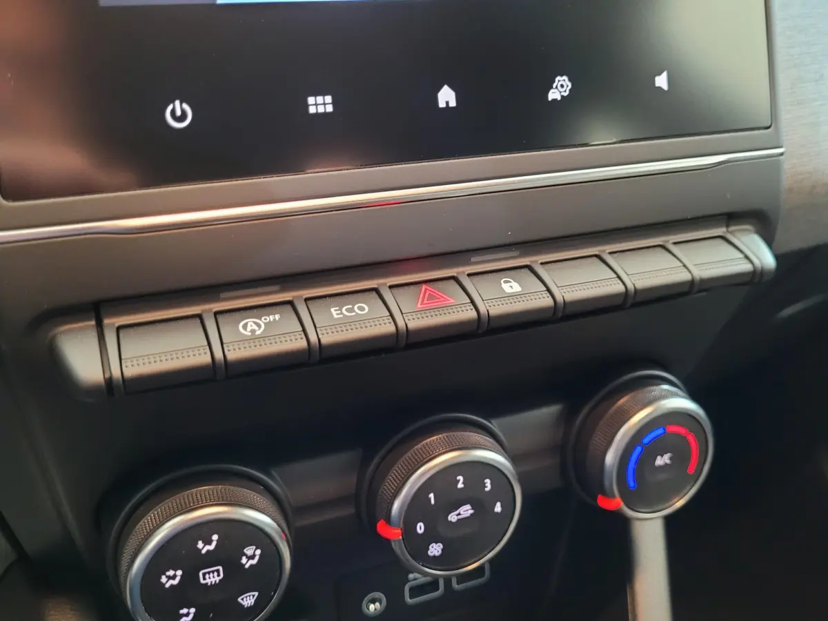 Gros plan sur la console centrale de la Renault Clio bleu, montrant les commandes de climatisation et les boutons de fonction.