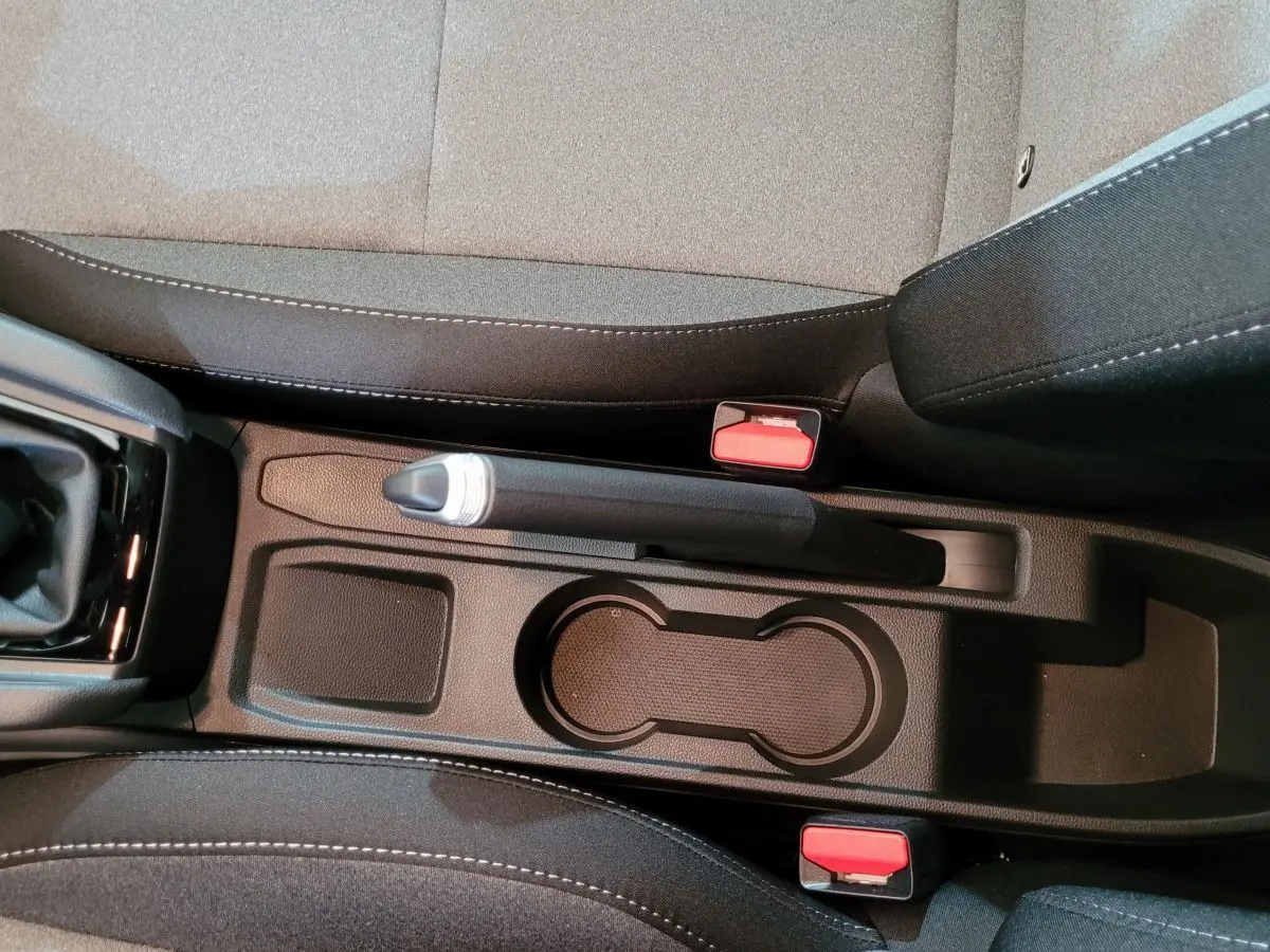 Vue plongeante sur la console centrale noire de la Renault Clio Evolution Blue dCi 100 avec frein à main manuel et sièges tissu gris.