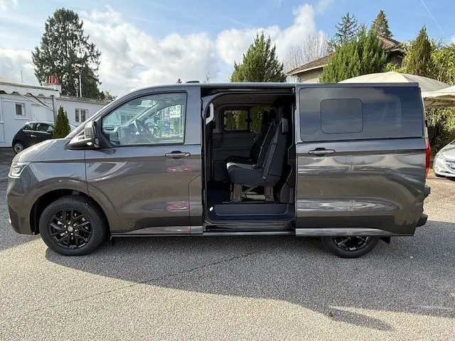 Vue latérale droite d'un Volkswagen Transporter T7 ProCab graphite Dust avec porte coulissante ouverte et sièges visibles.