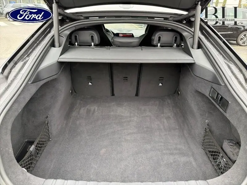 Coffre ouvert vu de l'arrière d'une BMW Série 4 Gran Coupé 420iA Saphirschwarz métallisé, intérieur noir et banquette rabattable.