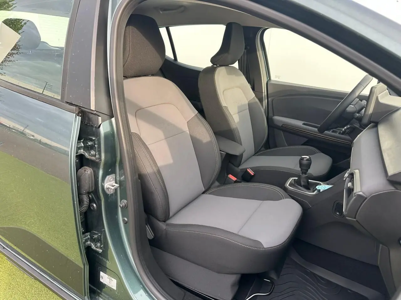 Vue intérieure côté conducteur de la Dacia Sandero III Stepway vert cèdre, montrant sièges et levier de vitesse manuel.