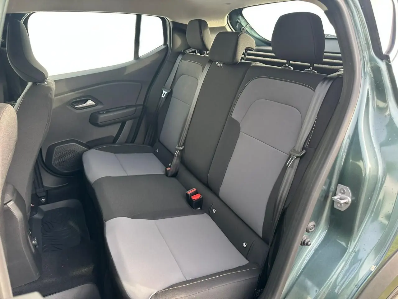 Vue côté droit de la banquette arrière bi-ton gris et noir du Dacia Sandero III Stepway vert cèdre avec porte ouverte.