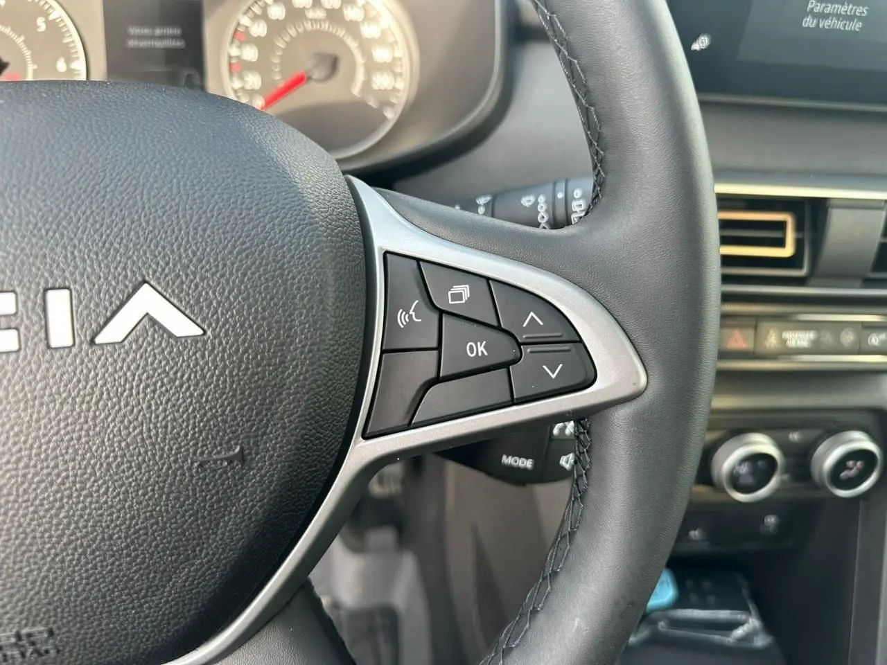 Gros plan sur le volant côté droit d’une Dacia Sandero III Stepway 2025, avec commandes intégrées et tableau de bord en arrière-plan.
