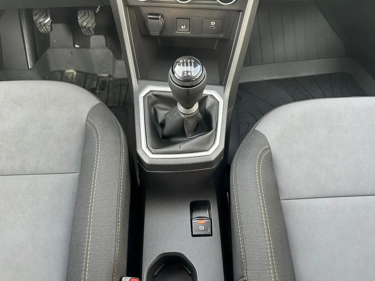 Vue rapprochée de la console centrale intérieure avec levier de vitesse manuel et frein de parking électrique sur Dacia Sandero Stepway.