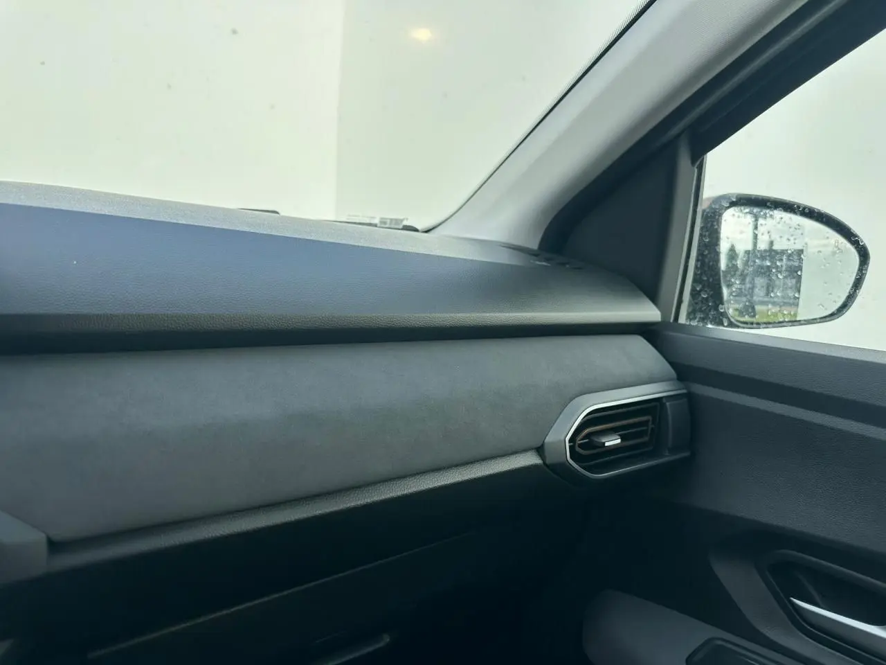 Vue intérieure côté passager avant de la Dacia Sandero III Stepway 2025, tableau de bord et aérateur noirs.