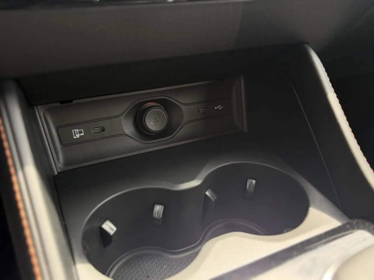 Gros plan sur l'accoudoir central avant noir du MG Motor EHS 1.5 Hybrid+ 224 Luxury avec porte-gobelets et prises USB.