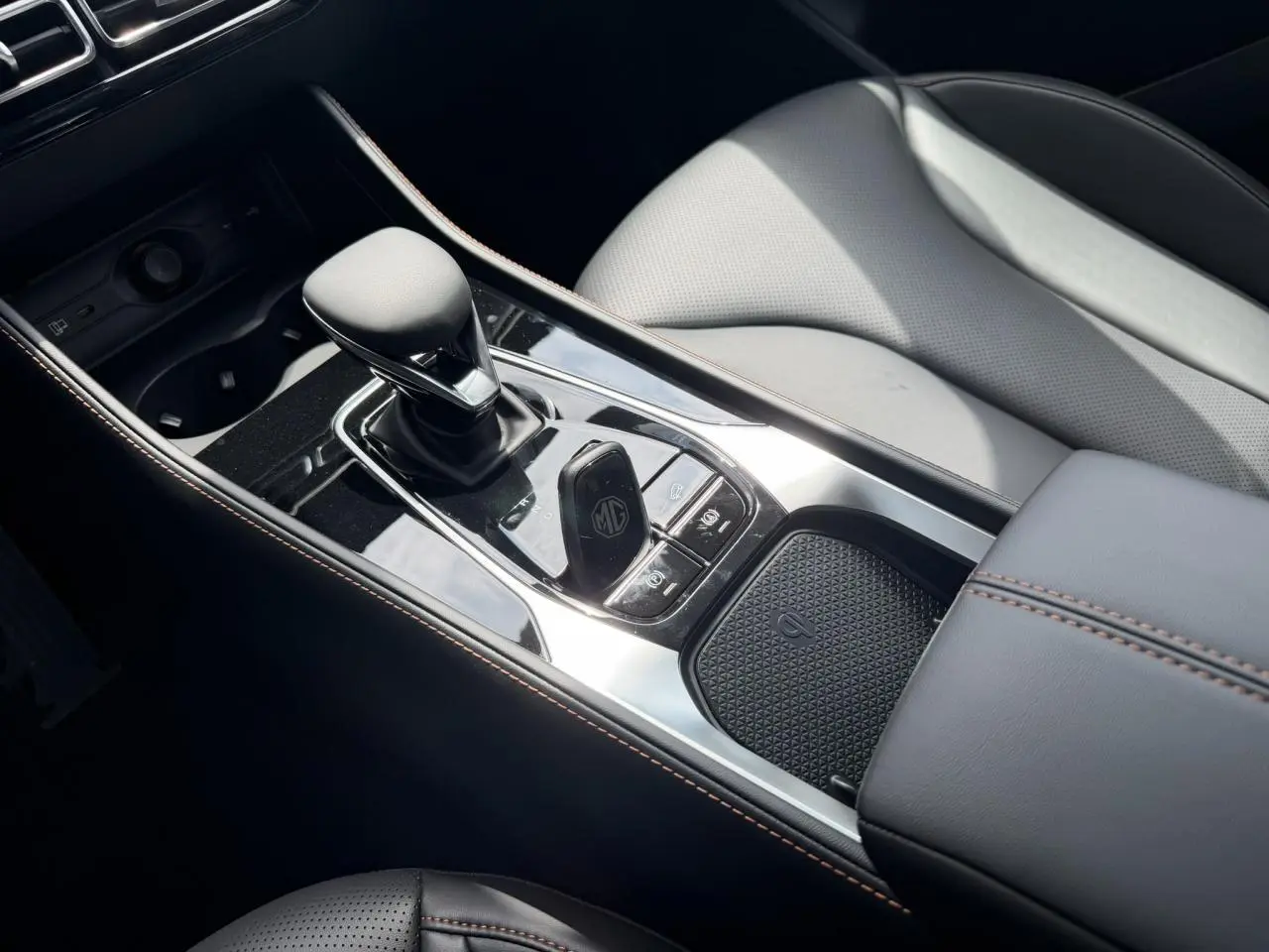 Vue rapprochée de la console centrale noire du MG Motor EHS 1.5 Hybrid+ 224 Luxury avec levier de vitesses et accoudoir.