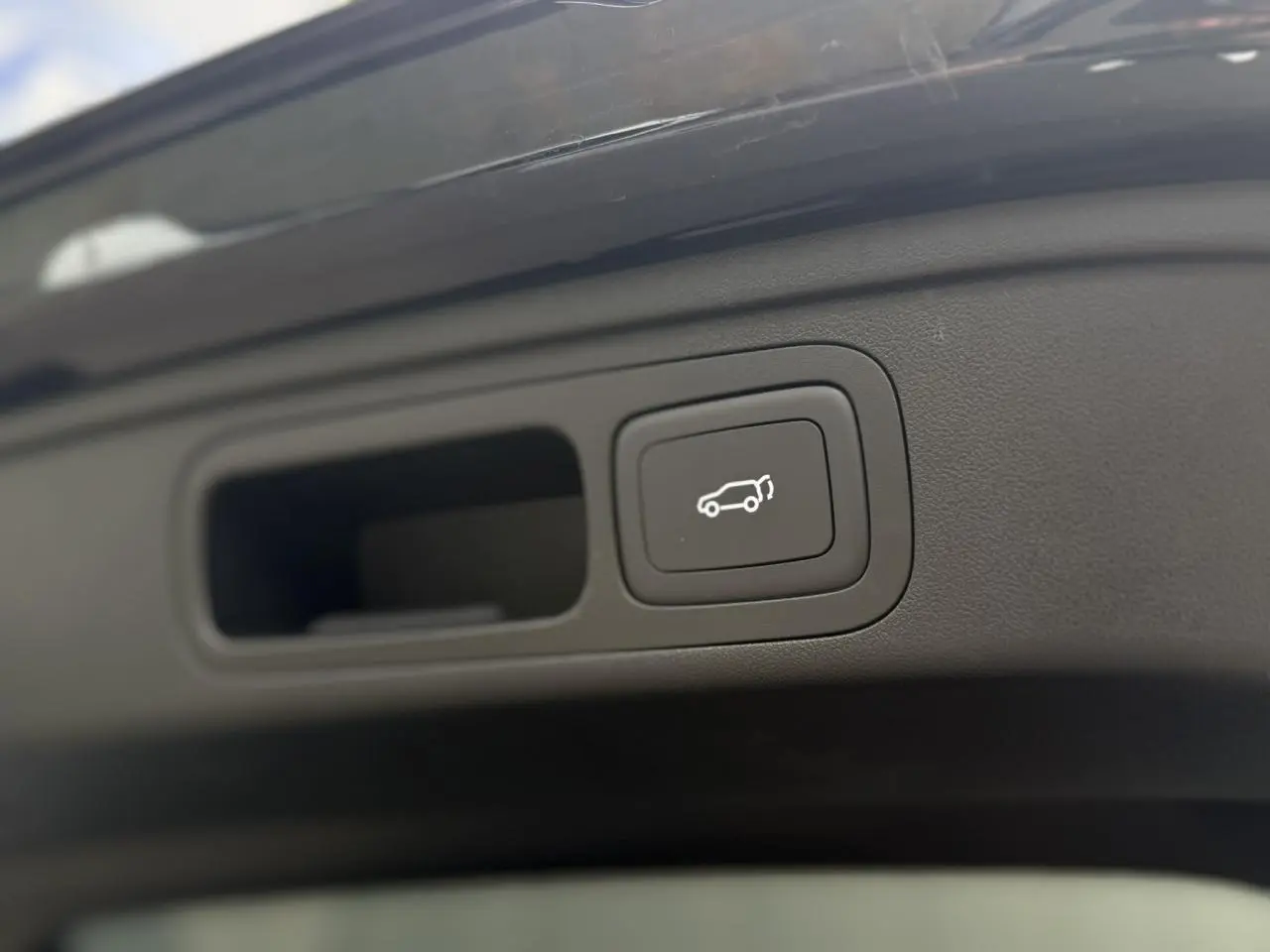 Gros plan sur le bouton d'ouverture électrique du hayon du MG Motor EHS 1.5 Hybrid+ 224 Luxury noir.