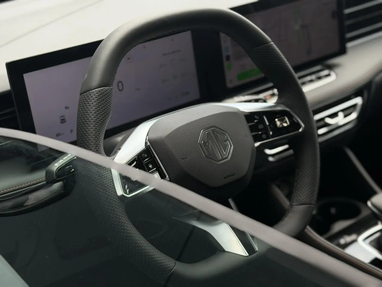 Vue rapprochée du volant noir perforé MG EHS 1.5 Hybrid+ 224 Luxury avec tableau de bord numérique et écran tactile.