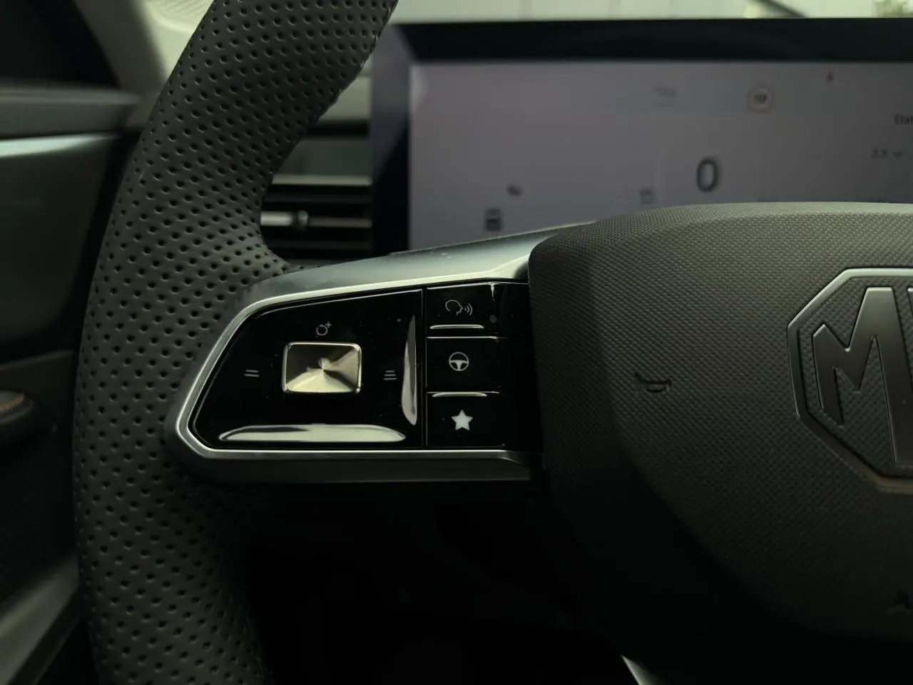 Gros plan sur la partie gauche du volant noir perforé du MG MOTOR EHS 1.5 Hybrid+ 224 Luxury avec commandes intégrées.