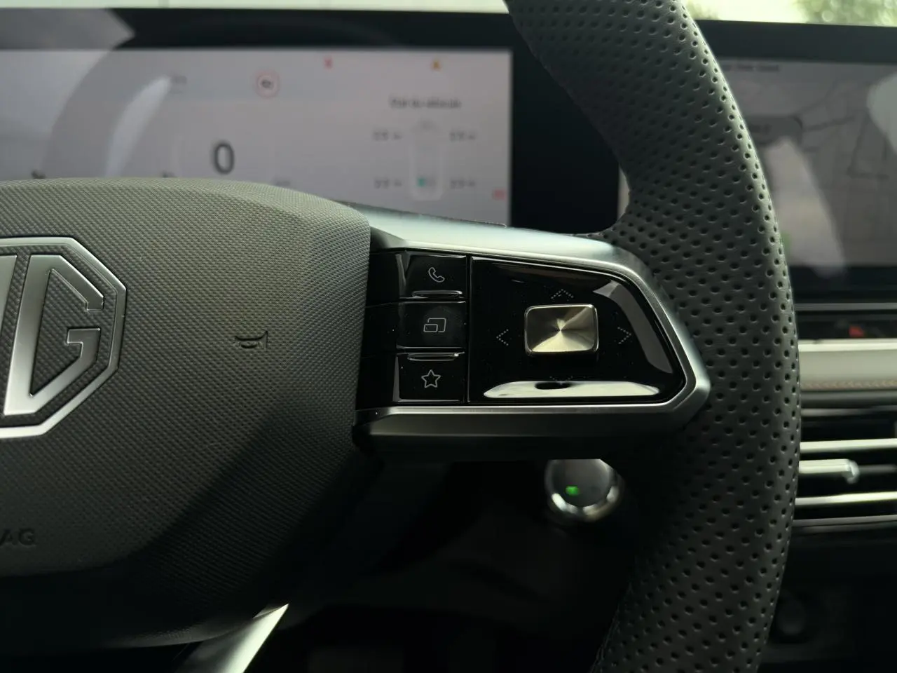 Gros plan sur le côté droit du volant noir perforé du MG MOTOR EHS 1.5 Hybrid+ 224 Luxury avec commandes intégrées.