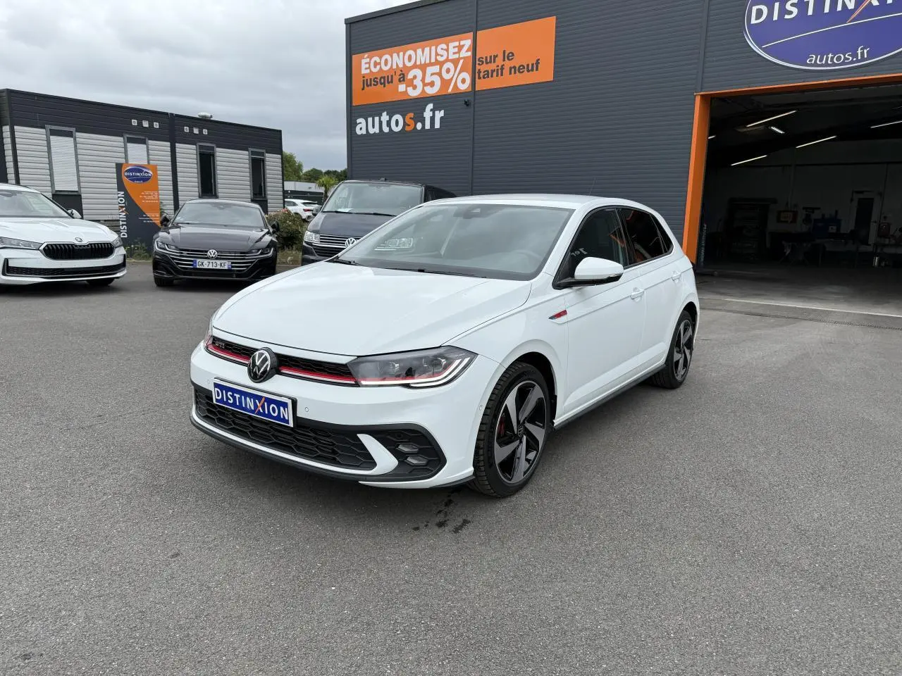 Volkswagen Polo GTI blanc pur vue 3/4 avant droit avec jantes noires et calandre rouge sur parking extérieur.